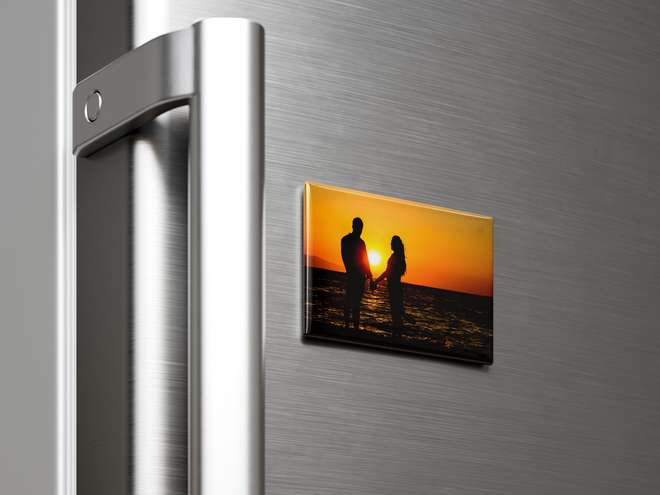 Prostokątny magnes ze zdjęciem pary na plaży o zachodzie słońca przyczepiony do lodówki.