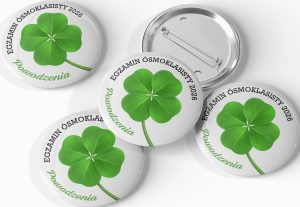 Uśmiechnięci uczniowie z przypinkami 56mm na plecakach po egzaminie ósmoklasisty, prezentujący własny wzór wspierający przed testem.